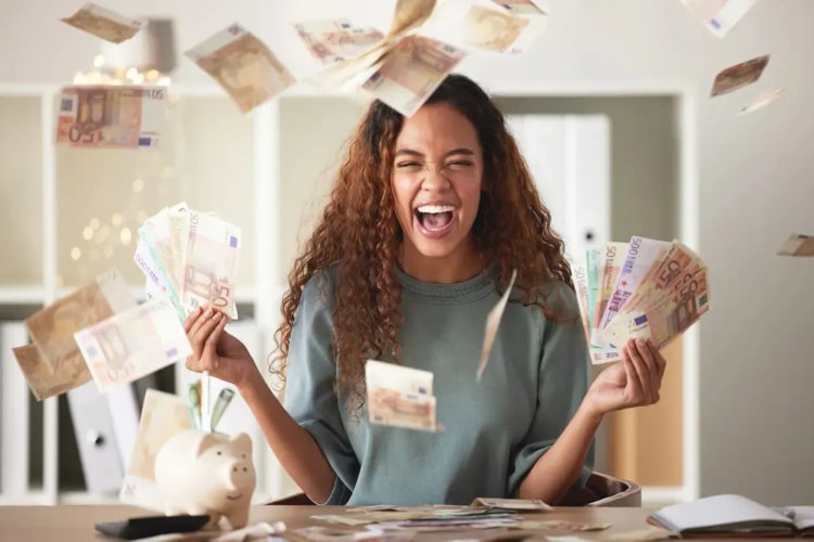 Jeune femme souriante tenant de nombreux billets de banque, symbolisant l’augmentation de son pouvoir d’achat après avoir changé d’assurance emprunteur